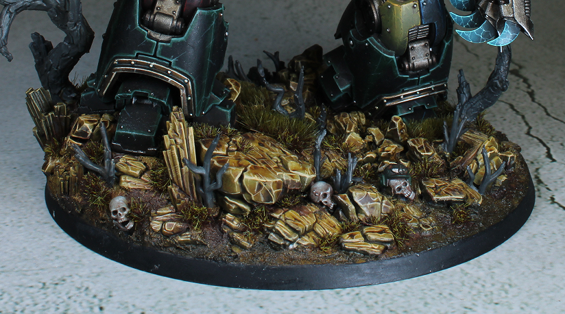 Layered ochre rocks, dark earth, sparse tufts, and green armored feet